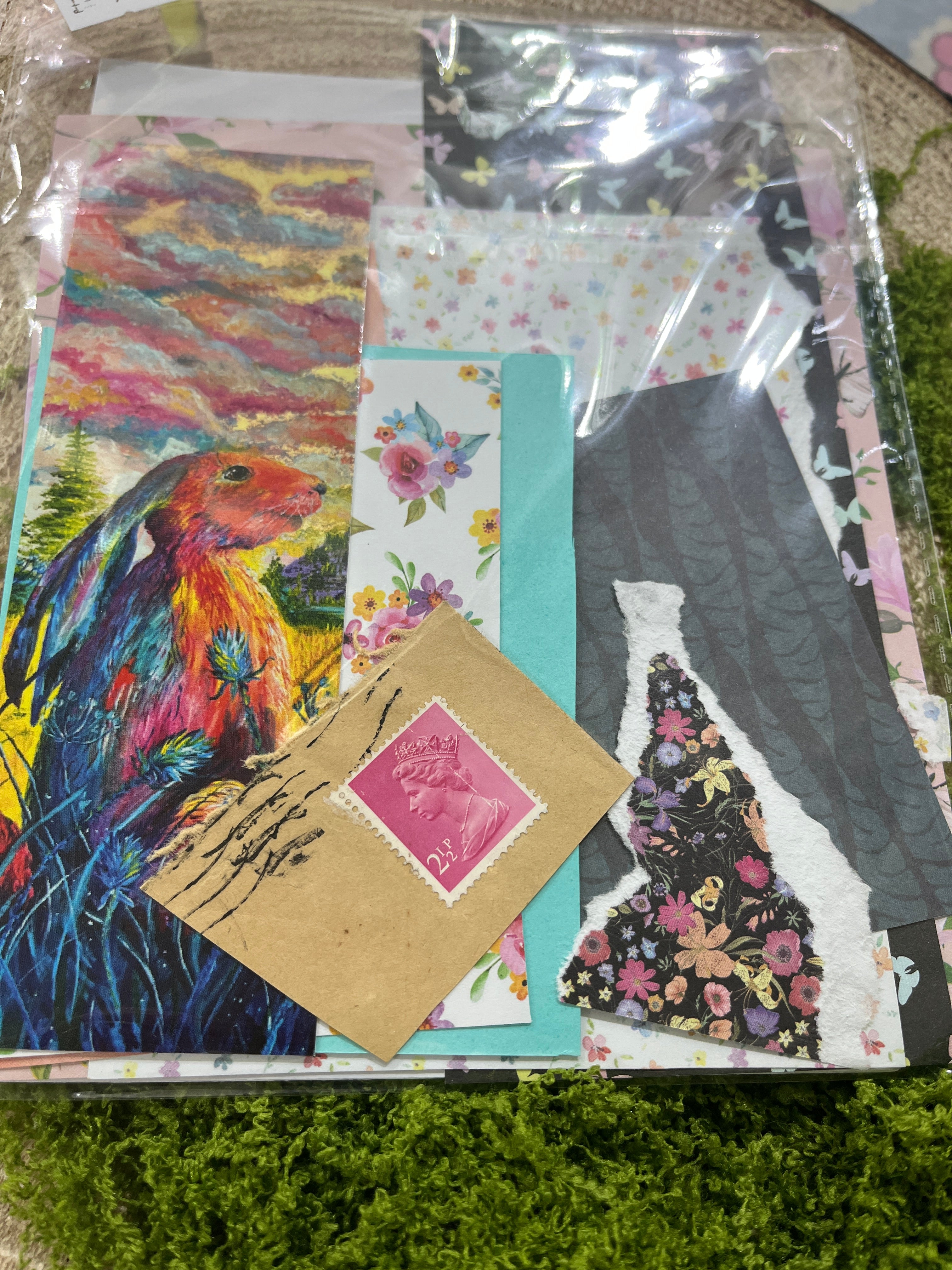 Collection of colorful greeting cards and a stamp on a textured surface with greenery in the background
