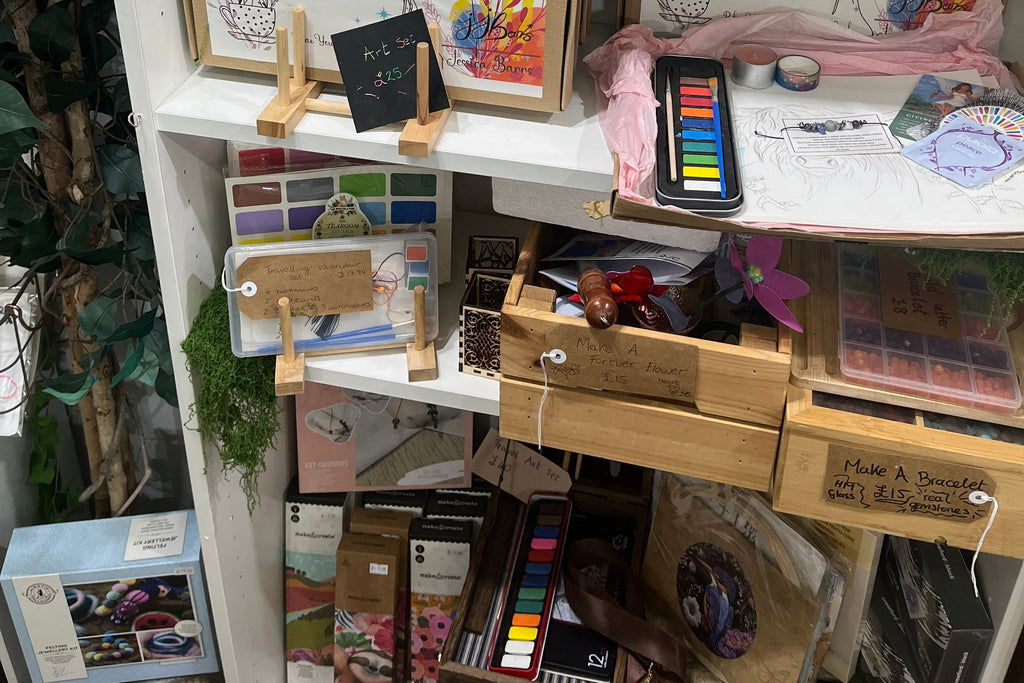 Display of art supplies and framed artwork on a shelf.