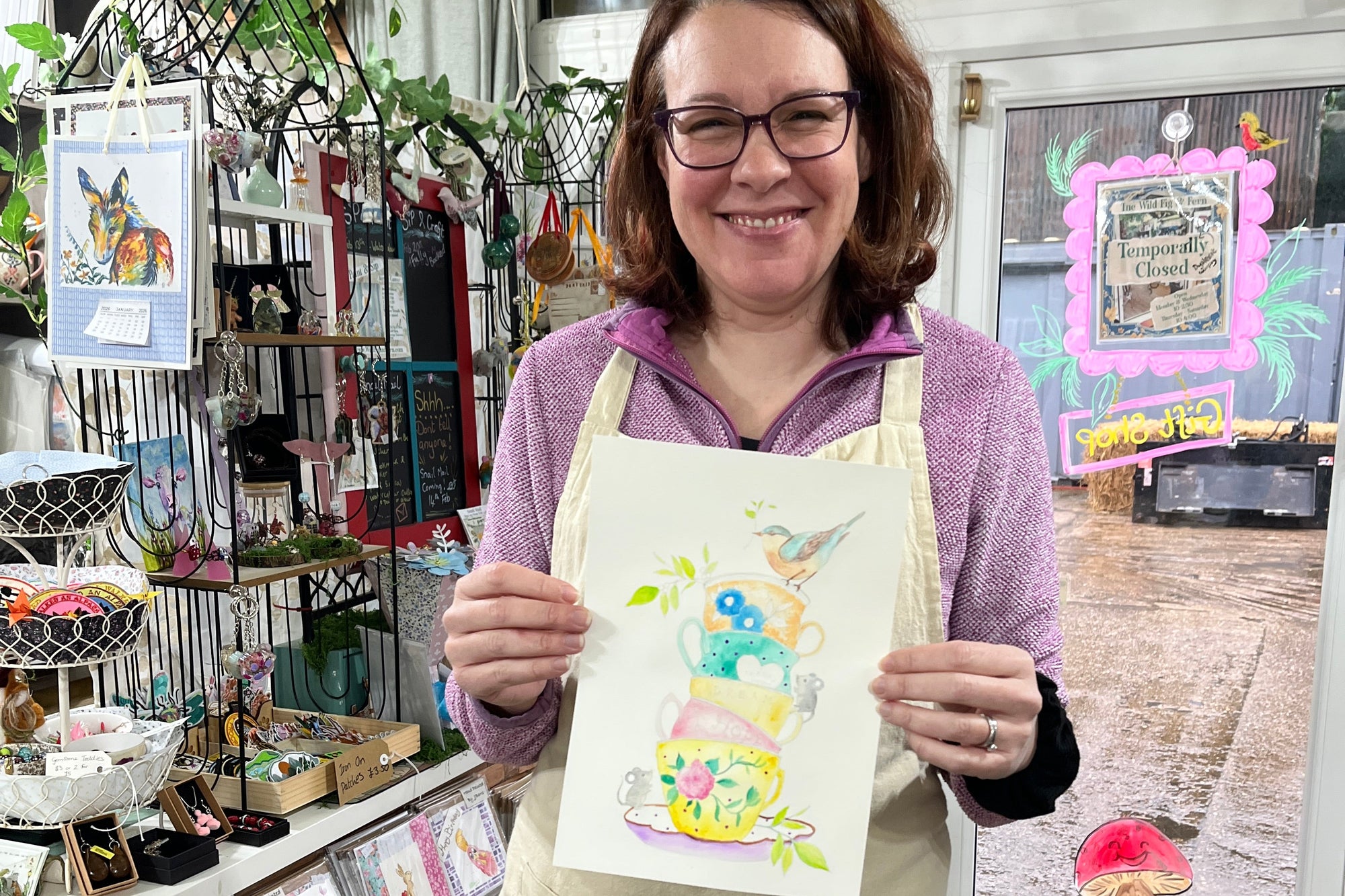 Person holding a colorful drawing in front of a display of artwork